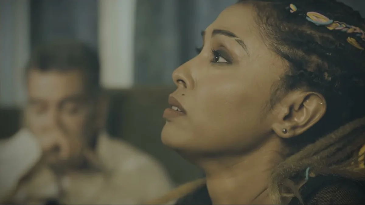 A woman looking upward in warm light, a still from TEH, The Layer