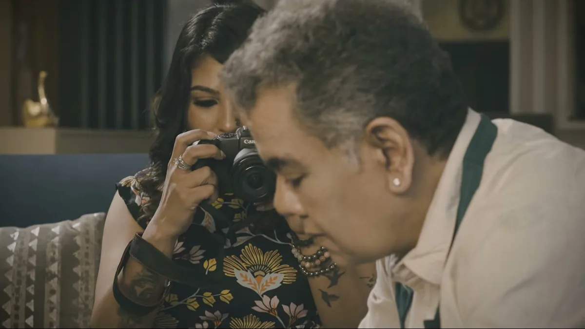 A man holding a camera to his eye beside a woman, a still from TEH, The Layer