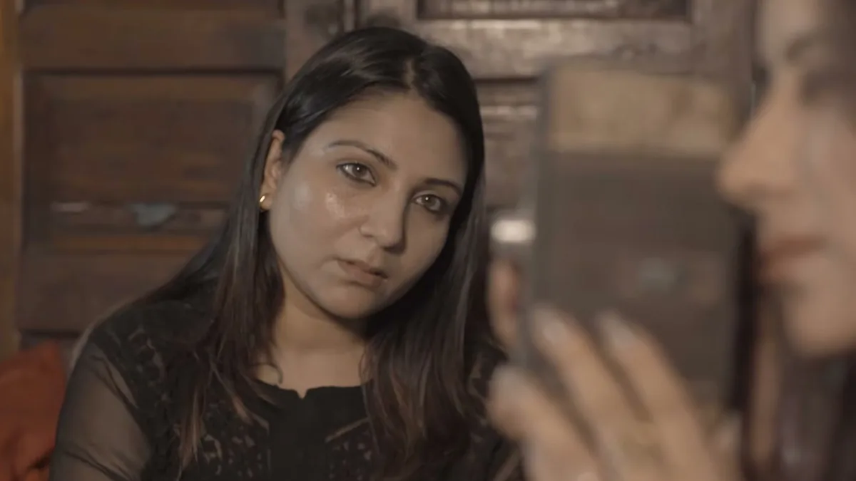 A woman holding a mirror to her face, a still from Ek Mausiqi ka Dabba