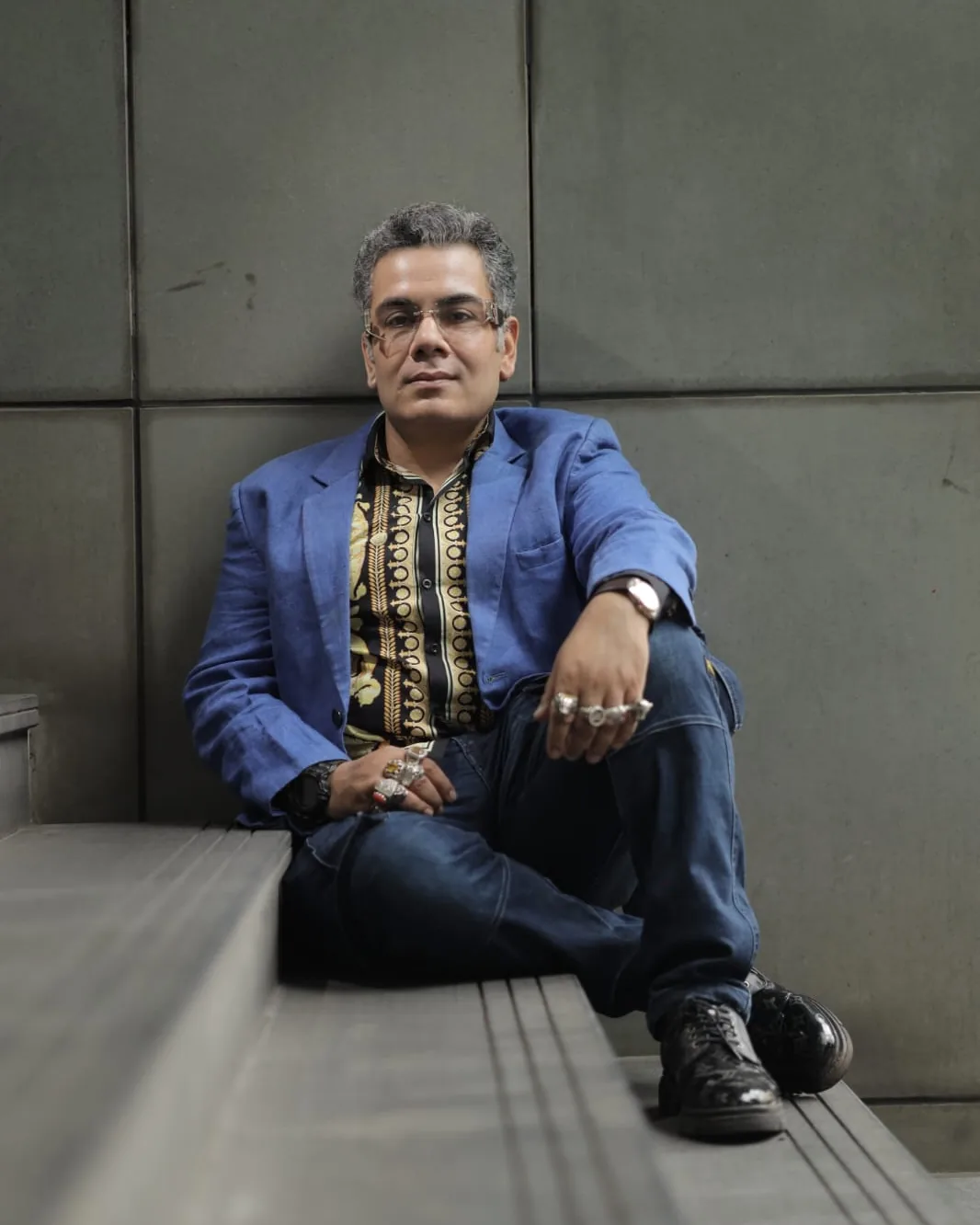 Sudeep Ranjan Sarkar seated in thought against a stone wall