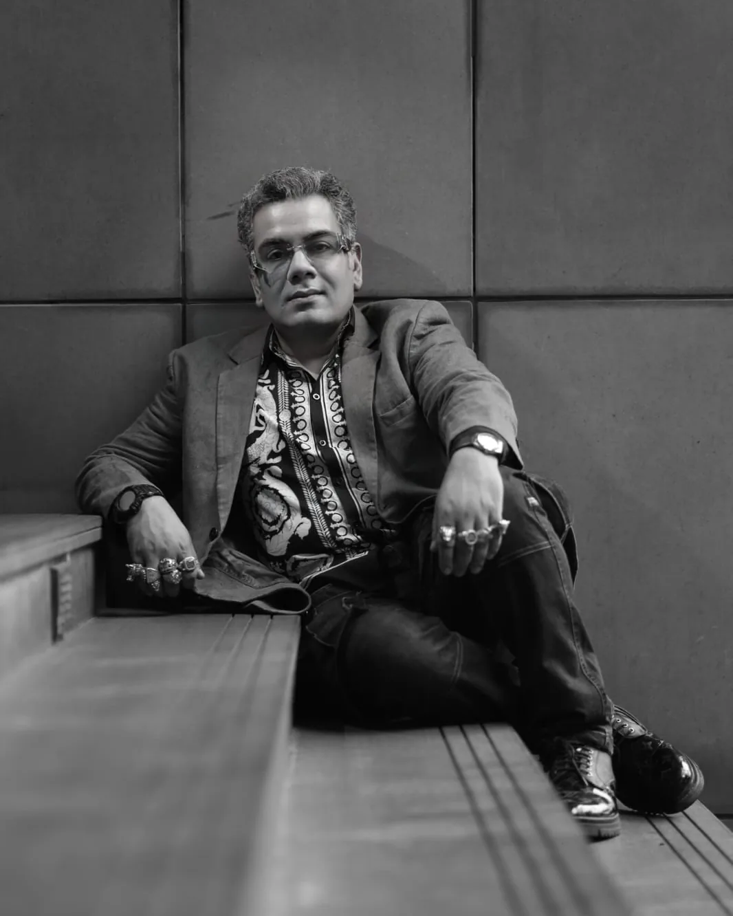 Sudeep Ranjan Sarkar seated against a stone wall, black and white